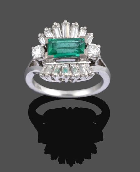 An Emerald and Diamond Cluster Ring, the central step cut emerald flanked by two round...