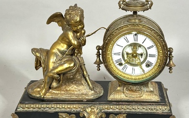 Black slate and Gilt metal French mantle clock with a full figure of Cupid next to the circular dial with urn finial and Roman Numeral chapter ring raised on animal paw feet. 15 x 17 1/2 inches.