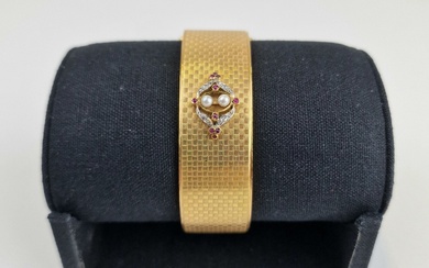 Bracelet manchette rigide ouvrant, en or jaune 750 ‰, à décor de damiers et centré...