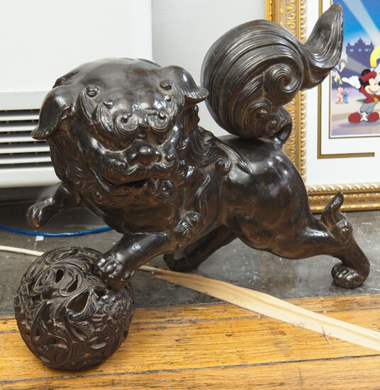 A CHINESE IRON FOO LION RESTING ON BALL