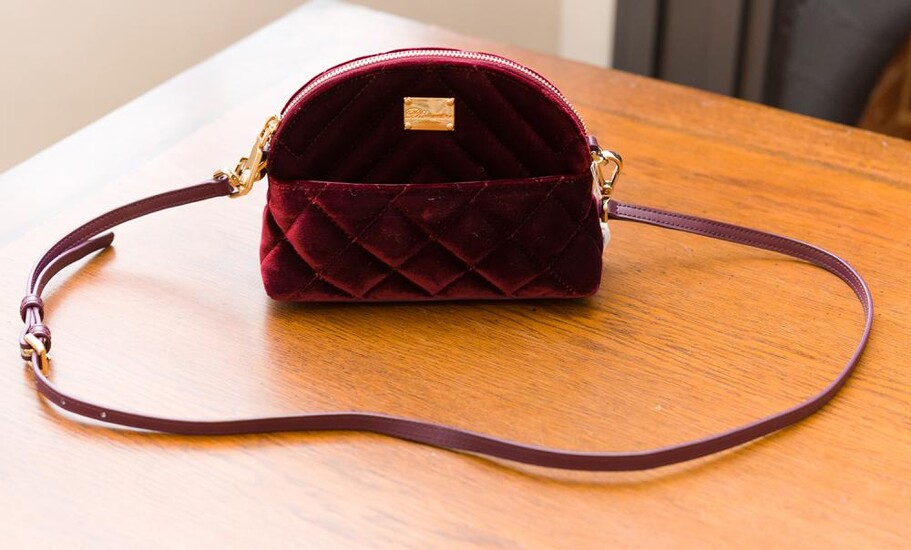 A CROSSBODY BAG BY BLUEMARINE - Styled in burgundy velvet with matching leather trim and gold metal hardware, with detachable should...