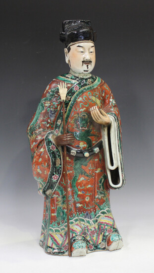 A Chinese famille verte enamelled porcelain figure of an immortal, late Qing dynasty, modelled stand