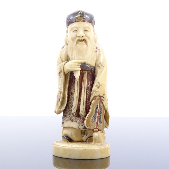 A Japanese carved and painted ivory okimono depicting a Sage...