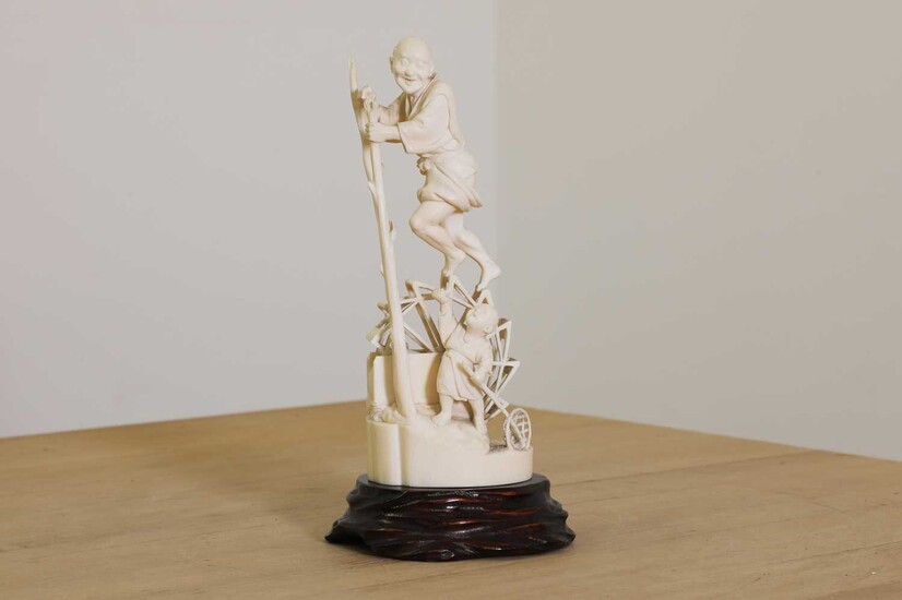 A Japanese solid carved ivory figure of a man turning a waterwheel