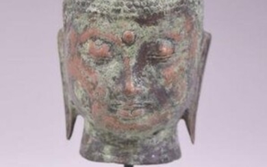A SOUTH EAST ASIAN METAL BUDDHA HEAD, raised upon a