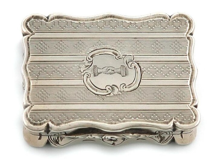 A Victorian silver vinaigrette, by Edward Smith, Birmingham 1848, rectangular form, with bands of engine-turned decoration, the cover with a crest of two shaking hands, the interior with a silver-gilt pierced and engraved foliate scroll grille, length...