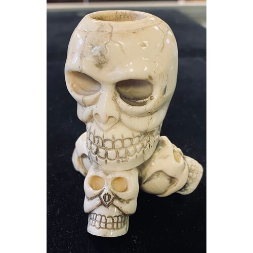 A bone candlestick, carved skulls, 7 cm high