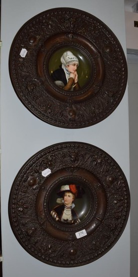 A pair of circular brass plaques with central porcelain plaques...