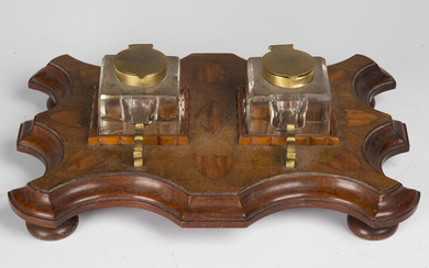 An early 20th century mahogany and satinwood inkstand, fitted with two glass inkwells on a serpentin
