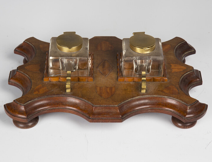 An early 20th century mahogany and satinwood inkstand, fitted with two glass inkwells on a serpentin