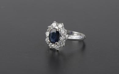 Daisy ring in 18k white gold scratched with a dark blue sapphire in a setting of ten round brilliant cut diamonds.