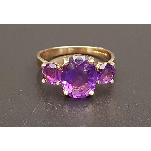 GRADUATED AMETHYST THREE STONE RING the central oval cut ame...