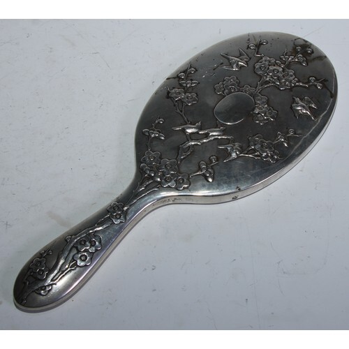 A Chinese silver hand mirror chased with birds and blossomin...