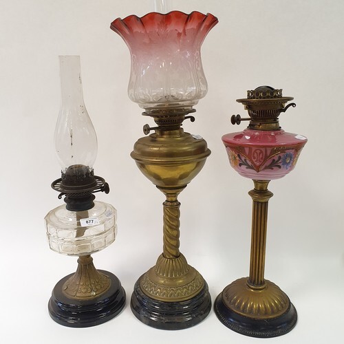 A brass oil lamp, with a cranberry lamp shade, 74 cm high, a...
