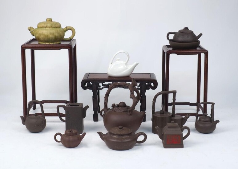 A collection of Yixing pottery, Chinese, of modern manufacture, to include; eight teapots of varying sizes and designs and a teapot stand, tallest 19cm high, together with; a white porcelain tea pot and a green matt teapot with lattice design, and...