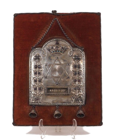 A gem-set Torah shield, the silver plated panel with three bells dependent designed with a Star of David at its centre flanked by two garnet-set columns and surmounted by a turquoise and garnet-set crown, a 'Yom Kippur' token within the rectangular...