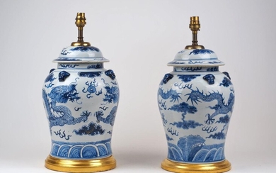 A pair of Chinese blue and white vase lamps and covers, 20th century, the bodies decorated with dragons, on giltwood bases, 36cm high (2) It is the buyer's responsibility to ensure that electrical items are professionally rewired for use.