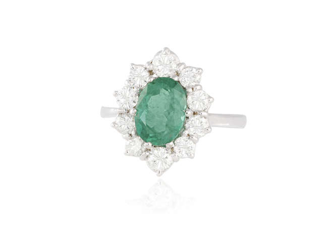 Description AN EMERALD AND DIAMOND CLUSTER RING The oval-shaped...