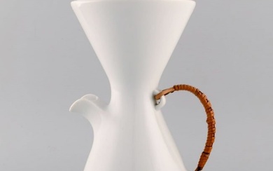Freeman Lederman. Large modernist jug in white glazed ceramics with wicker handle. Mid-20th century.
