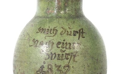 Large gift pot Wohl Germany or k.k. Austria, dat. 1832, pottery with reddish-brown body, green glaze all around, frontal inscription in black ''mich durst nach einer wurst'' and dat. 1832'', bulbous corpus with ribbon handle, h: 32 cm. Strong signs of...
