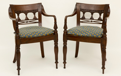 Paar achttiende/negentiende eeuwse koloniale armstoelen in acajou met gecanneleerde poten, een in ajour gesculpteerde rug en zitting in rotan ||pair of 18th/19th Cent. colonial armchairs in mahogany