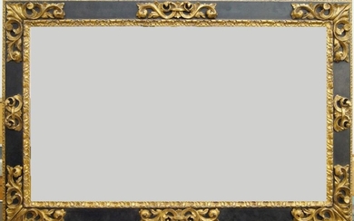 A Carved Parcel Gilded and Ebonised Spanish Style Plate Frame, late 20th century, with leaf and shield sight, tied leaf centres and foliate scrollwork corners, lapped demi-fleur back edge, 62.7 x 108 cm (sight)