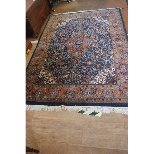 A Persian rug, dark blue ground, wide multi-coloured border,...