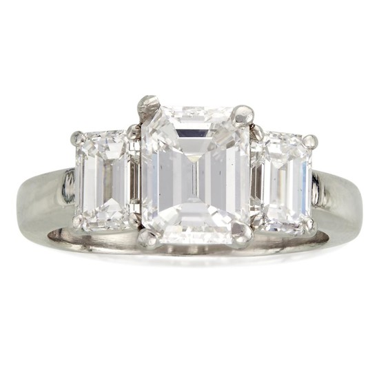 A diamond and platinum ring centering an emerald-cut diamond...