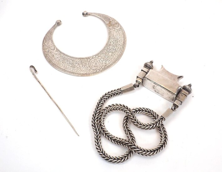 A white metal prayer box necklace, unmarked, the necklace designed with a thick, squared neckchain to a shaped box with pagoda design terminals to either side fastening the box closed, together with a crescent-shaped white metal collar...