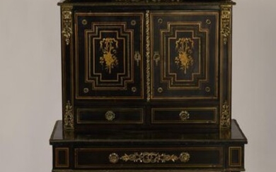 Blackened wood and brass inlaid happiness of the day desk, decorated with arabesques and musical trophies. Opening by two leaves and a drawer in belt. Late 19th century period. H : 132, W : 75, D : 49 cm. (One slit on the top; inside of the drawer...