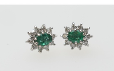 Pair of emerald and diamond cluster earrings, the central ov...