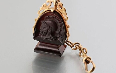 Stamp in sardony, the grip decorated with a profile of a man wearing a helmet, the mute stamp, it is embellished with a 750 thousandths yellow gold frame with cut-out decoration of foliage held by a chain and a gold snap hook, 19th century, Gross...