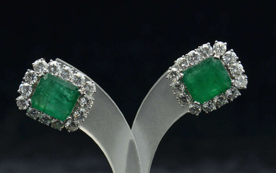White gold earrings with diamonds and emeralds White gold, 18K, 28 natural diamonds (round brilliant cut, 5.3 ct, 3.6-3.8 mm, SI), 2 emeralds (cornered rectangular step cut, 7.6 ct, 11.5x10.5 mm, EI1). Weight 12.65 g, 20.12x17.50 mm. There is a...