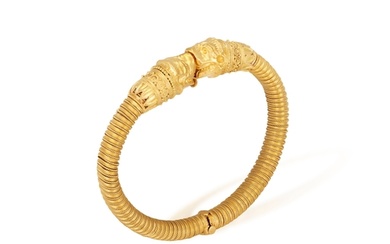 A 22K GOLD BANGLE Of spring design, each terminal with oppo...