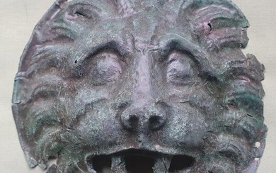 A Roman sheet bronze mount depicting a lion mask...