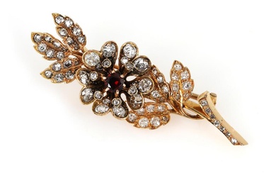 A garnet and diamond brooch in the shape of a flower set...