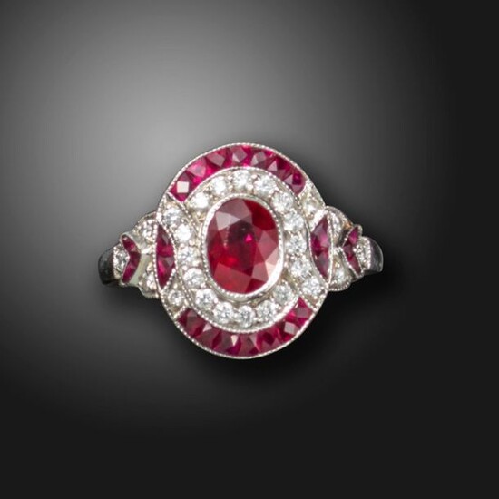 A ruby and diamond cluster ring, centred with an oval-shaped...