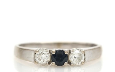 A sapphire and diamond ring set with a faceted sapphire flanked by...