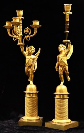 Pair of gilt bronze candelabra, each featuring a cherub on a guilloche base, standing on one foot, holding in its raised hand a horn with lights.