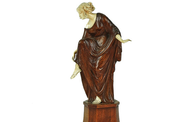 A CARVED IVORY AND WOOD SCULPTURE OF A FEMALE ADJUSTING HER SANDAL
