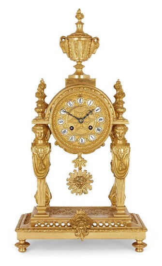 A French Louis XVI style gilt-bronze mantel clock, late 20th century, surmounted by an urn with goat head handles, the circular dial supported by caryatids, on a pierced trellis work base, 48cm high Please note that Roseberys do not guarantee...