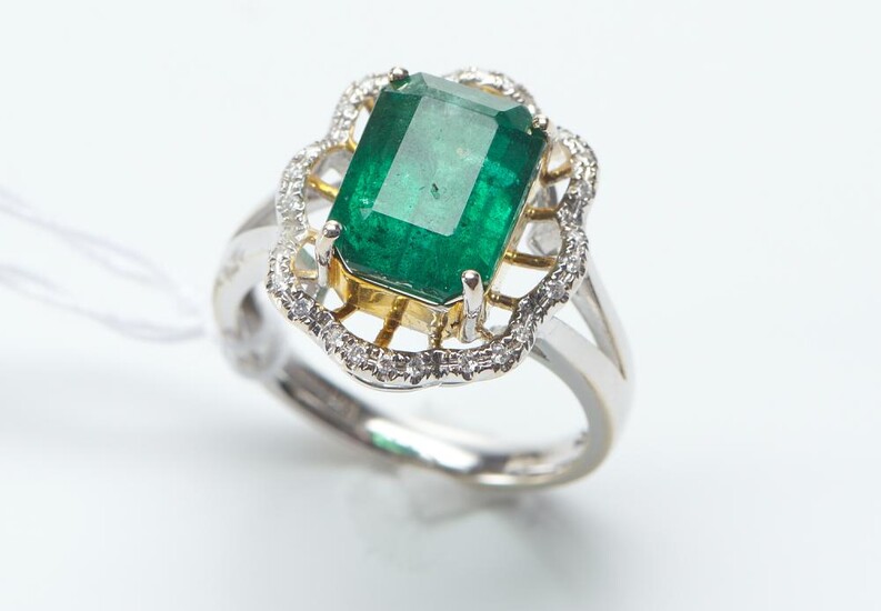 A ZAMBIAN EMERALD AND DIAMOND RING IN 18CT TWO TONE GOLD, THE EMERALD WEIGHING 4.71CTS, AND THE DIAMONDS TOTALING 0.13CTS, RING SI...