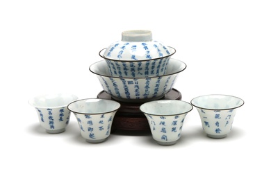A blue and white porcelain tea set comprising four teacups, one bowl and a covered teacup each painted with Chinese characters