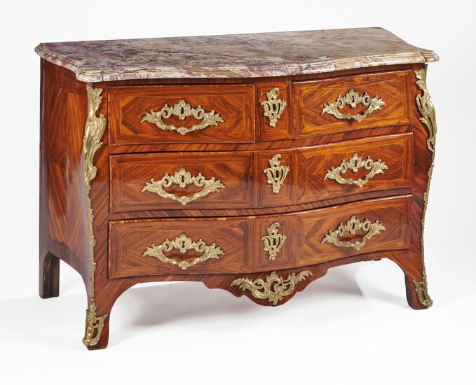 A curved chest of drawers in violet wood veneer, with framed fillets. It opens with five drawers on three rows framed by pinched uprights. Ornamentation of Rocaille bronzes: lock entrance, draw handles, apron, falls and sabots. Moulded, pink and...