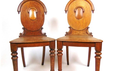 A pair of 19th century oak hall chairs, the oval...