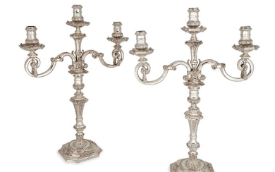 A pair of Asprey & Co. silver three light candelabra, London, c.1965, convertible to candlesticks, the scrolling branches with laurel swags supporting squared drip pans and foliate cast sockets, the knopped stems with foliate and mask motifs to...