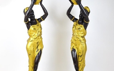 A pair of large cast bronze female blackamoor torcheres with gilt detail, raised on marble plinths.