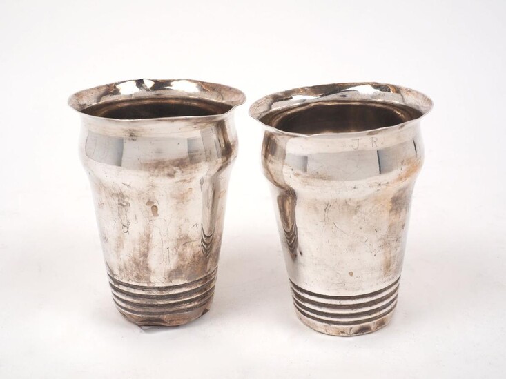 A pair of white metal cups, stamped T100 to bases, possibly Indian, of shaped cylindrical form with banded reeding to lower sections, 11.4cm high (2)