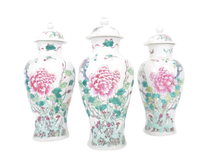 A set of three Chinese Yongzheng marked famille rose lidded vases. Each baluster vase decorated on white glazed grounds with scenes of peony tree and other fauna. Yongzheng six character mark to the underside. Rivet repairs to one, chips to lid on 2...