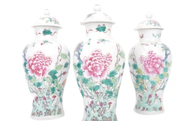 A set of three Chinese Yongzheng marked famille rose lidded vases. Each baluster vase decorated on white glazed grounds with scenes of peony tree and other fauna. Yongzheng six character mark to the underside. Rivet repairs to one, chips to lid on 2...